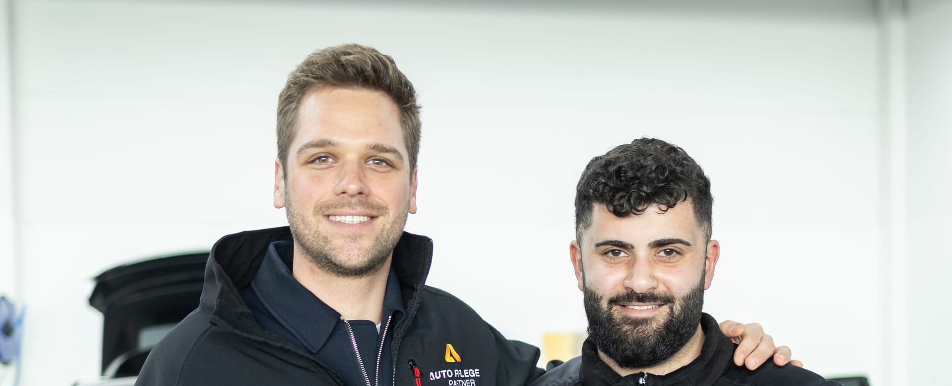 Two happy detailers in front of a car.